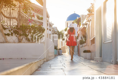 Santorini travel tourist brunette woman in red dress visiting famous white Oia village. 43884181