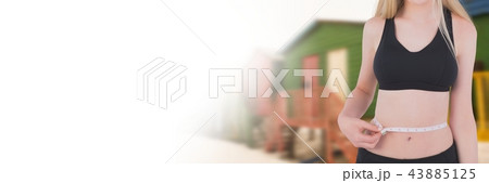 Woman measuring weight with measuring tape on waist near summer beach huts with transition 43885125