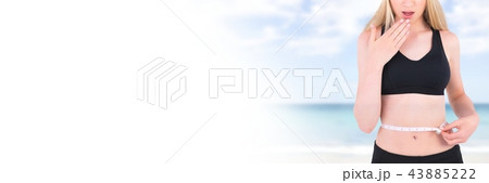 Woman measuring weight with measuring tape on waist on Summer beach with transition 43885222