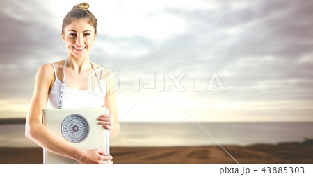 Woman holding weighing scales near sea 43885303