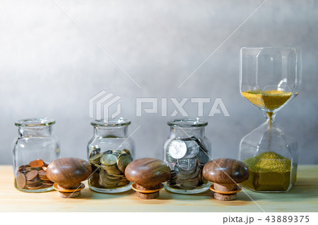 Coin jars and hourglass. Save money for retirement Coin jars and hourglass. Save money for retirement 43889375