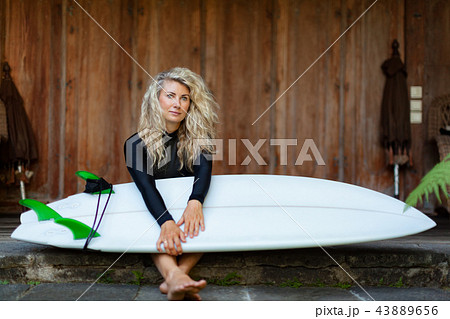 Girl with surfboard sit on veranda of beach villa Girl with surfboard sit on veranda of beach villa 43889656