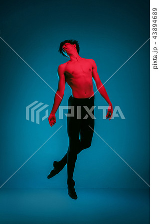 The male athletic ballet dancer performing dance on blue background. Studio shot. Ballet concept 43894689