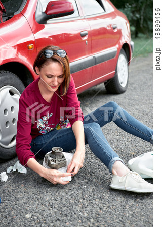 young girl sitting on the road by the red car  43899456