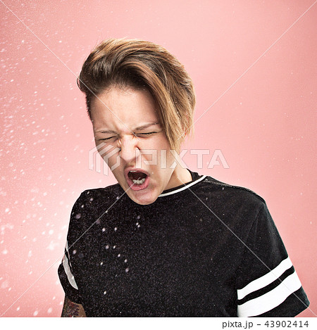 Young woman sneezing, studio portrait Young woman sneezing, studio portrait 43902414