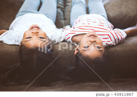 Two child girls are lying on their backs on sofa Two child girls are lying on their backs on sofa 43911907