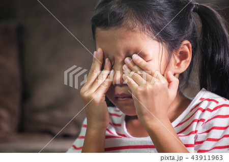 Sad child girl is crying and rubbing her eyes 43911963