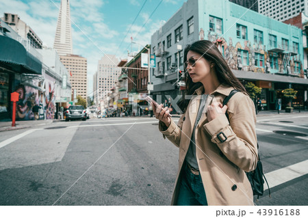 woman using cell phone while crossing the road 43916188