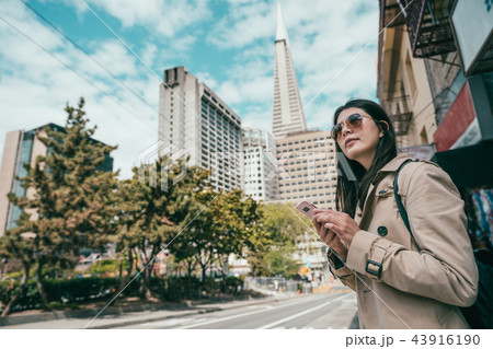 woman searching by phone standing in street 43916190