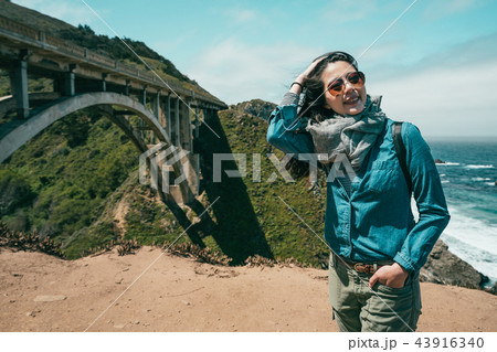 woman standing on cliff surrounded by sea 43916340