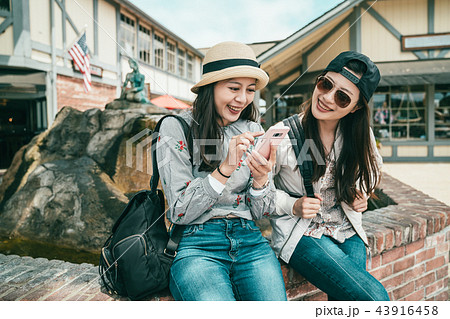 girls laughing while sitting to the fountain 43916458