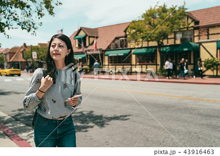 girl looking around while using phone and walking 43916463