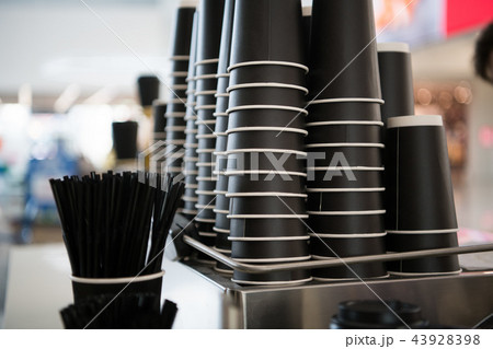 Black paper cups on a counter against the background of a blurred coffee bar at mall with takeaway Black paper cups on a counter against the background of a blurred coffee bar at mall with takeaway 43928398