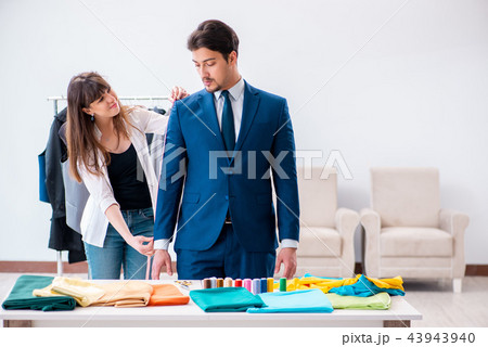 Professional tailor taking measurements for formal suit Professional tailor taking measurements for formal suit 43943940