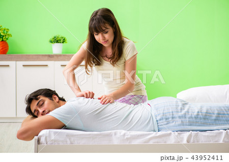 Woman doing massage to her husband in bedroom  43952411