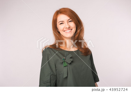 Fashion and people concept - Portrait of happy ginger woman smiling looking at camera over white 43952724
