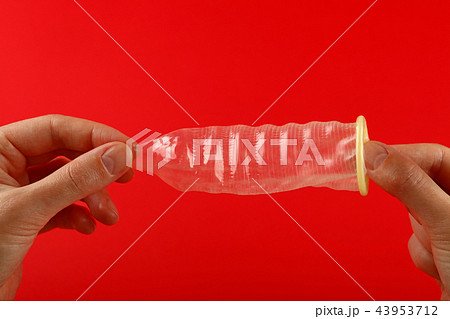 Close up woman hands holding open condom over red 43953712