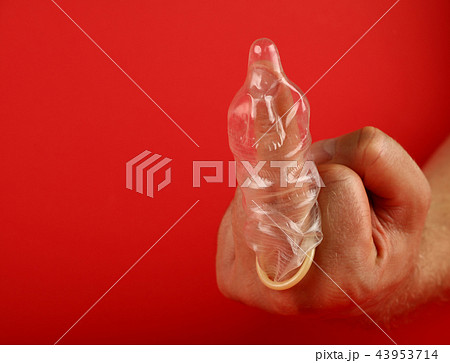 Close up man hand with condom on finger over red Close up man hand with condom on finger over red 43953714