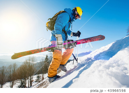 Male skier walking up the snowy hill in the Carpathians mountains carrying his skis Male skier walking up the snowy hill in the Carpathians mountains carrying his skis 43966598