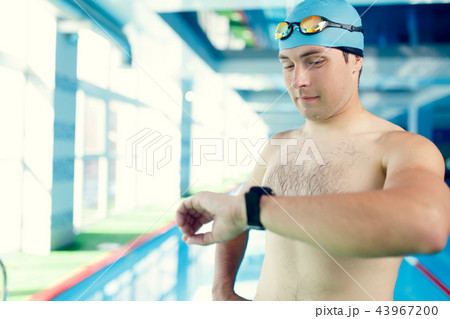 Image of young swimmer with timer on arm standing in pool during workout Image of young swimmer with timer on arm standing in pool during workout 43967200