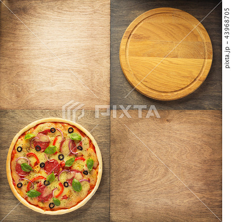 pizza and cutting board at wooden table 43968705