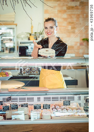 Salesgirl selling cheese in deli or supermarket 43969736