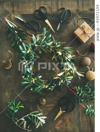 Flat-lay of Christmas decoration toys and wreath over wooden background Flat-lay of Christmas decoration toys and wreath over wooden background 43972104