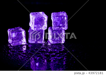 Purple ice cubes reflection on black table. 43972181