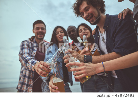 Happy friends clinking glass bottles of beer Happy friends clinking glass bottles of beer 43972493