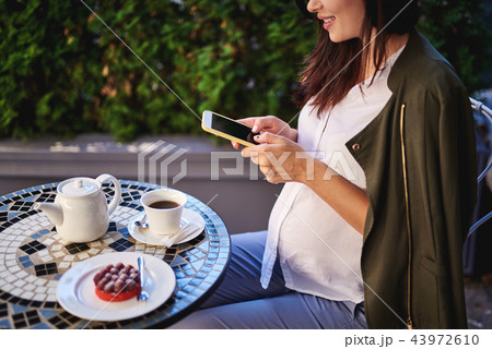 Lovely pregnant lady using cellphone in outdoor cafe Lovely pregnant lady using cellphone in outdoor cafe 43972610