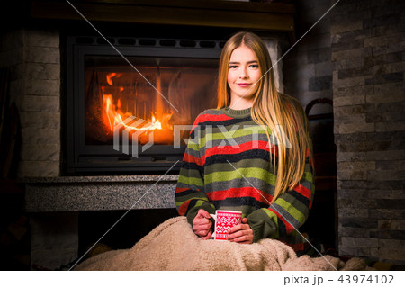 Girl having a cup of tea by the fireplace Girl having a cup of tea by the fireplace 43974102