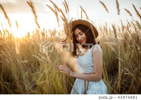 Woman in dress and straw hat holds wheat bouquet Woman in dress and straw hat holds wheat bouquet 43974881
