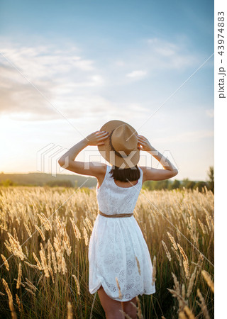Woman in dress walking in wheat field on sunset Woman in dress walking in wheat field on sunset 43974883