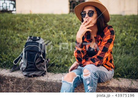 Female tourist in sunglasses smoke cigarettes Female tourist in sunglasses smoke cigarettes 43975196