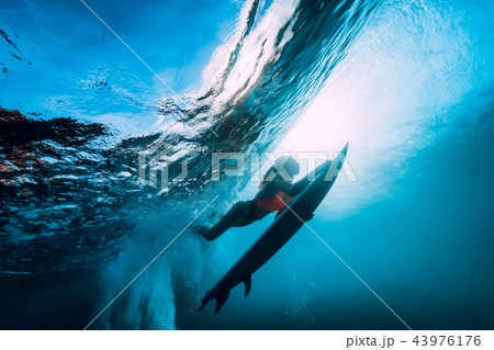 Surfer girl with surfboard dive underwater 43976176