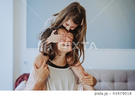beautiful little daughter piggybacking on her happy mother beautiful little daughter piggybacking on her happy mother 43979018