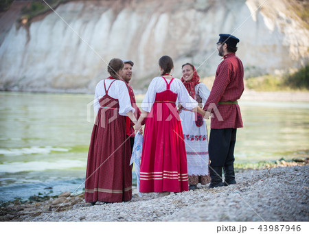 A group of people in Russian folk costumes dancing in a beautiful landscape, in the foreground is A group of people in Russian folk costumes dancing in a beautiful landscape, in the foreground is 43987946