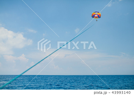 People flying on a colorful parachute towed by a motor boat 43993140