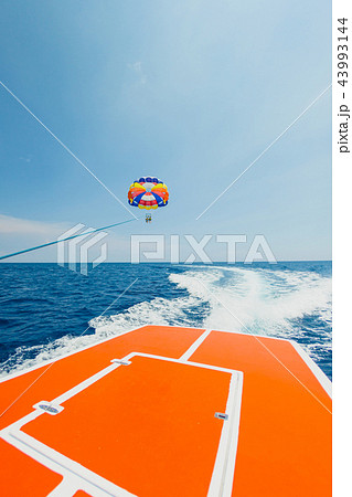 Couple of tourists flying on a multi colored parachute 43993144