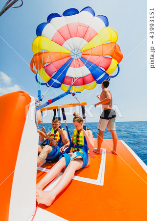 Couple of tourists prepearing to fly on a multi colored parachute 43993151