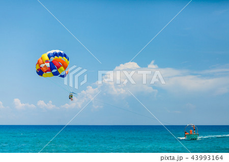 People flying on a colorful parachute towed by a motor boat 43993164