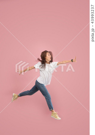 Freedom in moving. Pretty young woman jumping against pink background 43993237