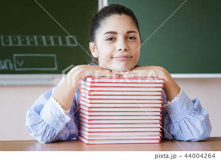 Smiling girl sits against blackboard in classroom 44004264
