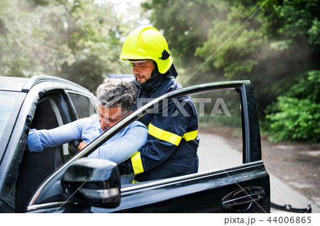 A firefighter getting an unconscious man out of the car after an accident. 44006865