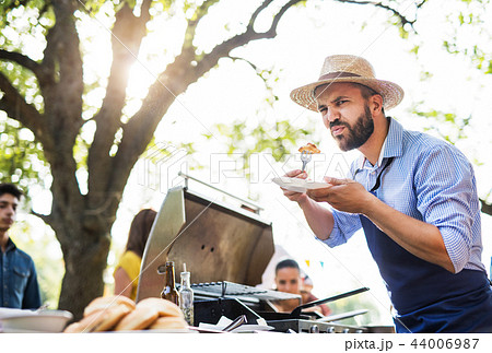 A mature man with family and friends cooking and serving food on a barbecue party. 44006987