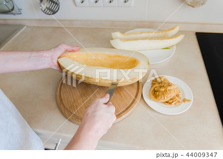 Woman cut melon and clean from seeds Woman cut melon and clean from seeds 44009347
