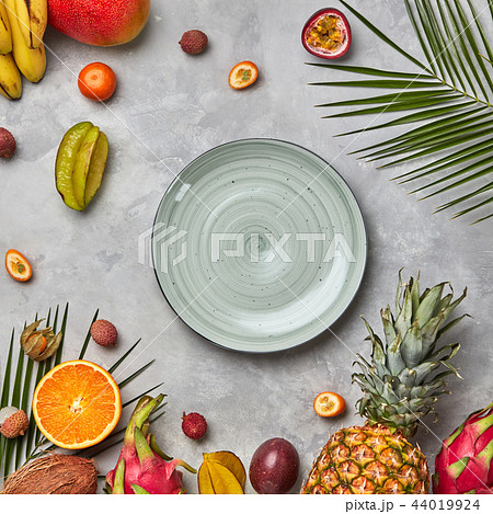 Juicy ripe tropical fruits, pineapple, papaya, mango, pineapple, green palm leaves and empty round 44019924