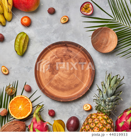 Various juicy exotic fruits, coconut, lychees, carom, pineapple, palm leaves and empty brown wooden Various juicy exotic fruits, coconut, lychees, carom, pineapple, palm leaves and empty brown wooden 44019933