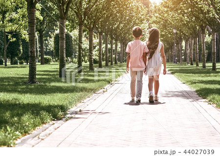 Friendship. Little boy and girl walking on the road in the park  44027039