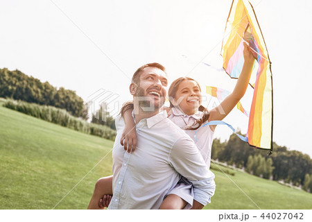 Weekend activities. Father carrying daughter on his back holding 44027042